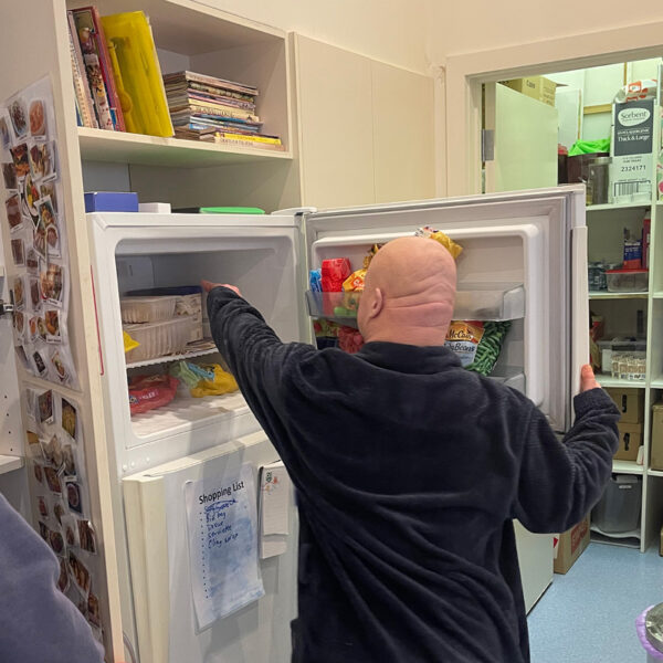Alkira participant Julian getting ingredients from the fridge to make dinner in his home.
