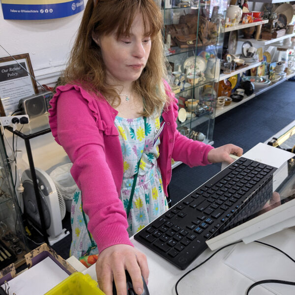 Alkira participant Greer uses the cash register at Vinnies.
