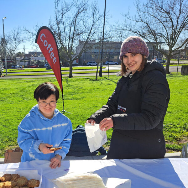 Alkira participant Chelsea wearing a beanie working at the AlkiraBiz coffee trailer outside the Box Hill Town Hall on Whitehorse Road in Box Hill.