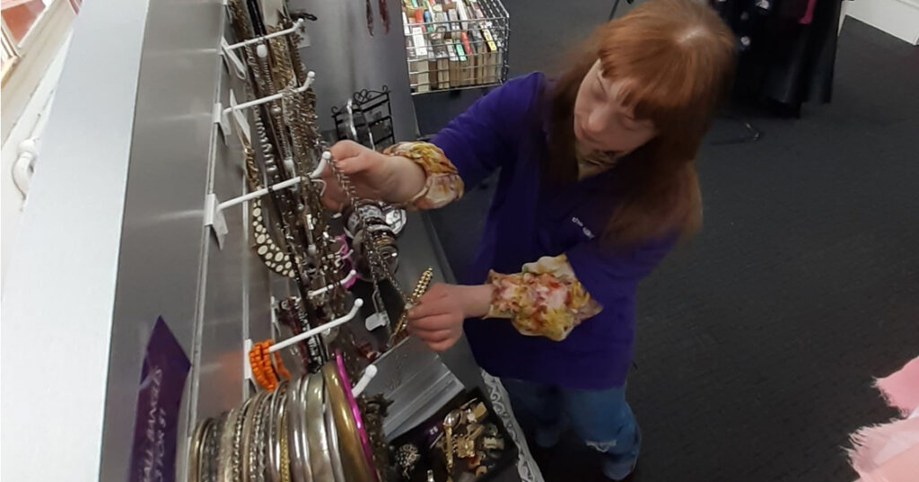 Alkira Networks participant Greer arranging the jewellery in the Alkira op shop as part of her programs.