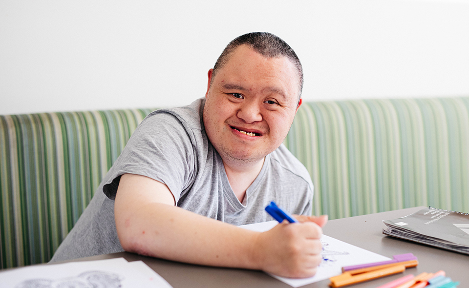 Alkira participant Isaac uses a blue marker to colour in artwork