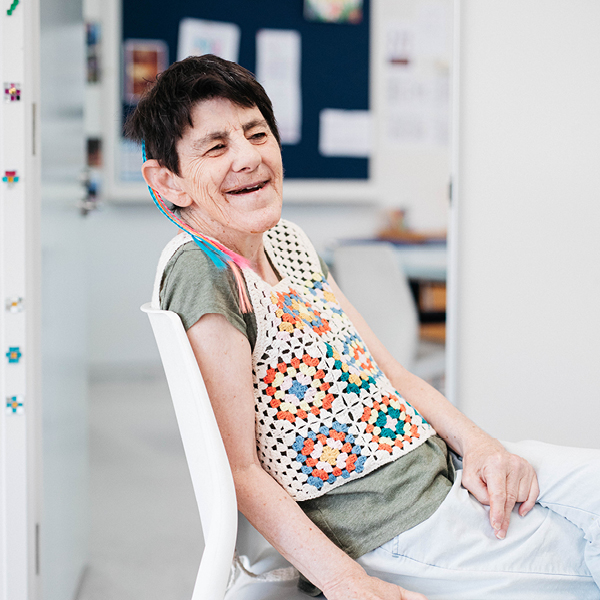 Alkira participant Bernie relaxed and smiling whilst sitting down in her Alkira day program.