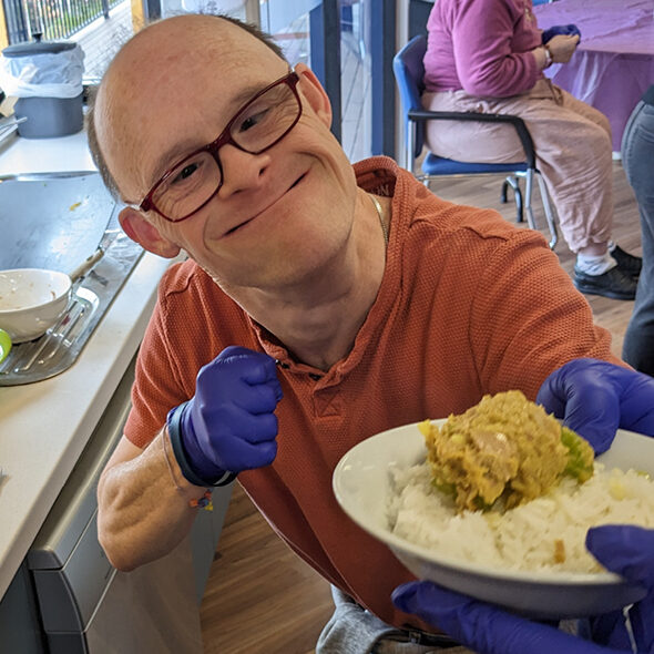 Alkira participant Eddie hands over plate of finished food that he made in his cooking program at Alkira’s Nunawading site.