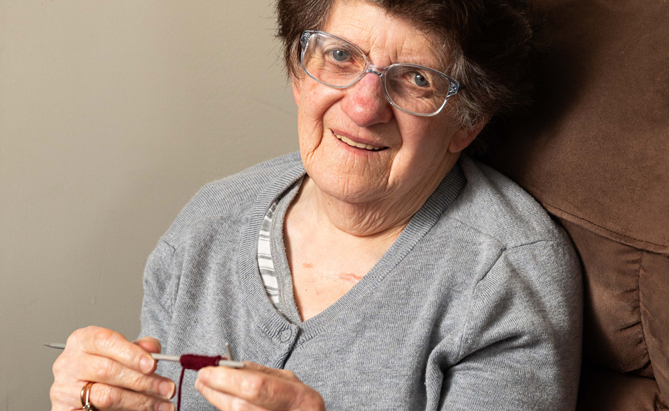 Alkira resident Junith knits on her couch in her SDA home, as she has done for the last 30 years.