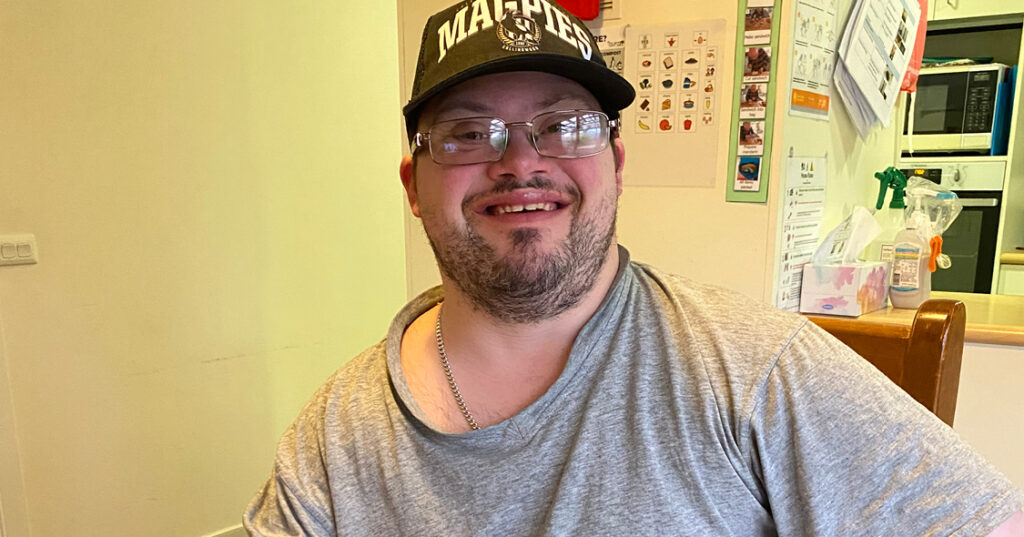 Robbie smiles at the camera in his new home whilst receiving supported independent living services.