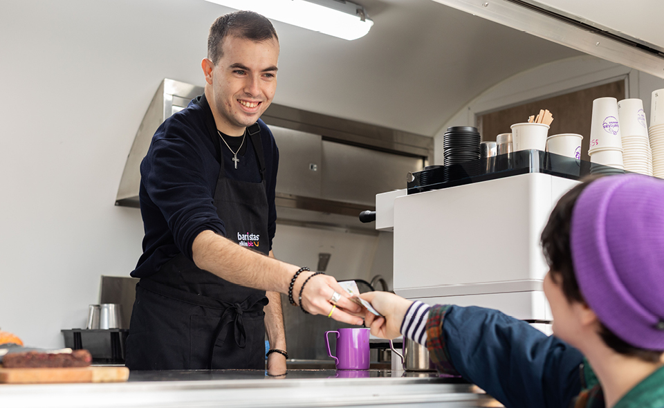Alkira participant Andrew accepts cash from customer for a takeaway coffee in the Baristas AlkiraBiz coffee trailer