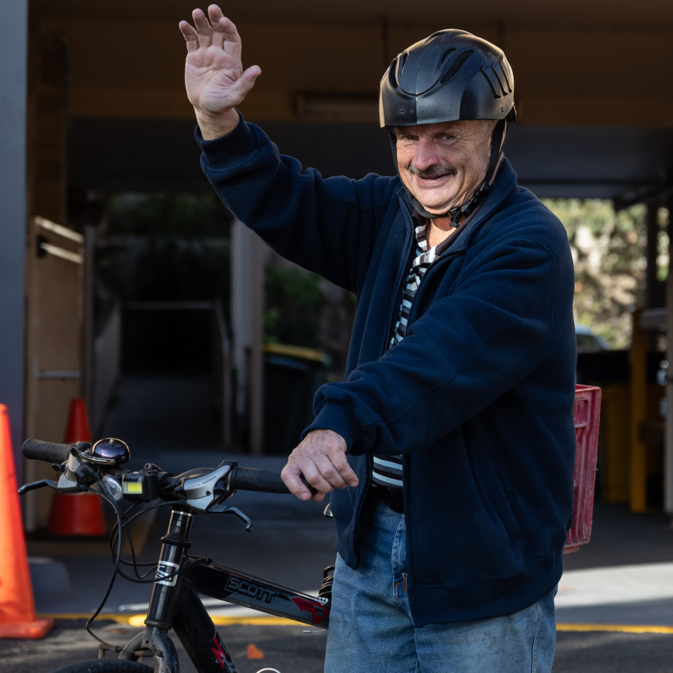 Alkira participant John Ritchie waves his hand whilst leaving on his bike
