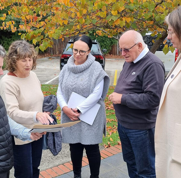 Alkira CEO Julia Canty-Waldron, Alkira CSO Bell Thompson and Alkira Growth Manager James Marshall stand with two Bendigo Bank representatives looking at plans for building a bungalow.