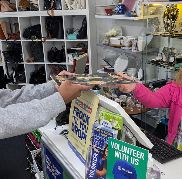Greer serves a customer at the counter at Vinnies op shop.