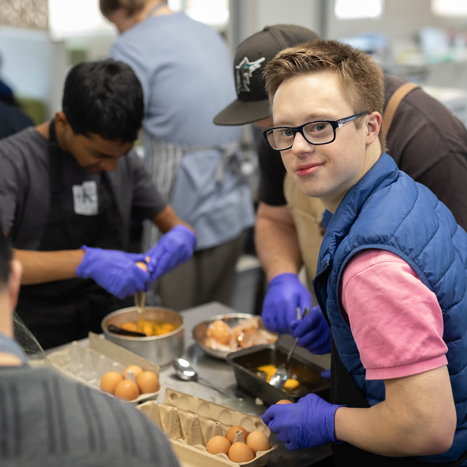 Alkira participant Matthew in his catering program helping the group whisk eggs