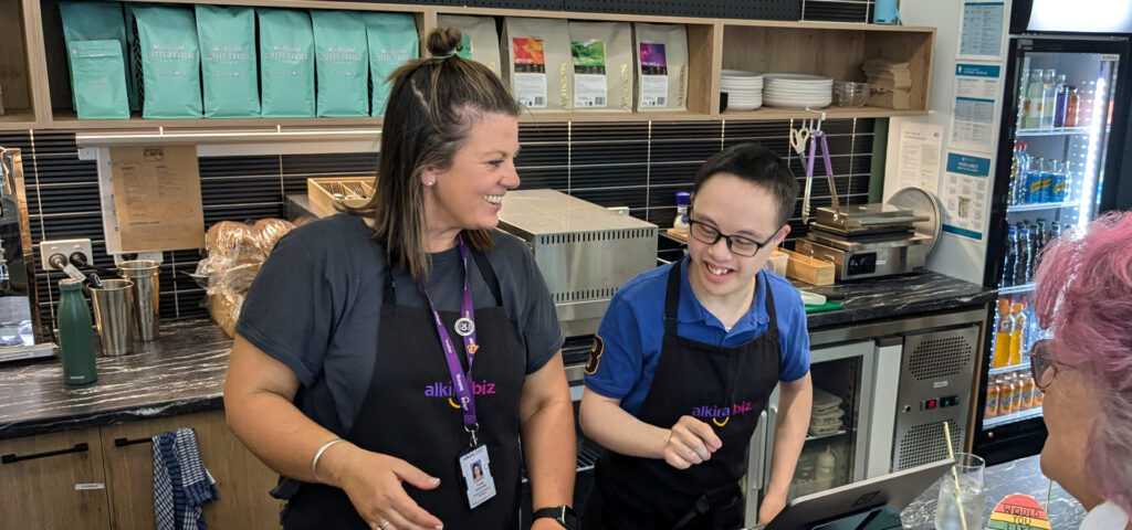 Alkira participant Matthew and Alkira staff member Yvette working at the register together at the AlkiraBiz café.